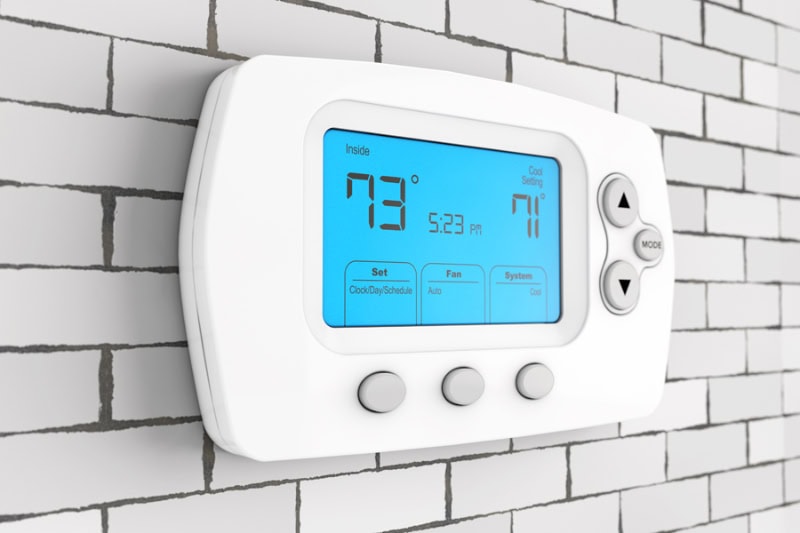 Thermostat Settings: On vs. Auto. Photo of a digital thermostat mounted on a wall.