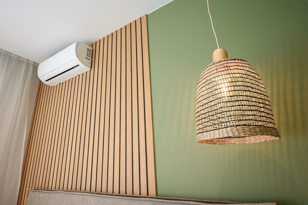 A modern interior with a wood slat wall, an AC unit, a green wall, and a woven pendant light.